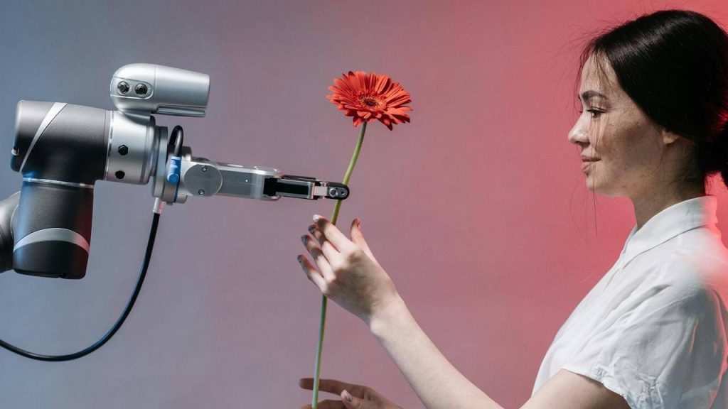 bras robotique tendant une fleur à une femme